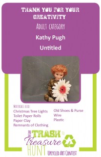 Trash to Treasure submission of a red-haired fairy man with wire wings holding a flower made of Christmas tree lights, toilet paper rolls, paper clay, remnants of clothing, old shoes & purse, wire, and plastic