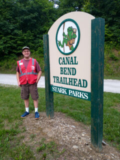 Trailblazer with stark parks vest on smiling next to Trailhead sign on Towpath Trail