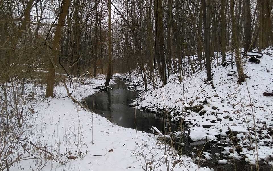 Creek running through land with snow on it
