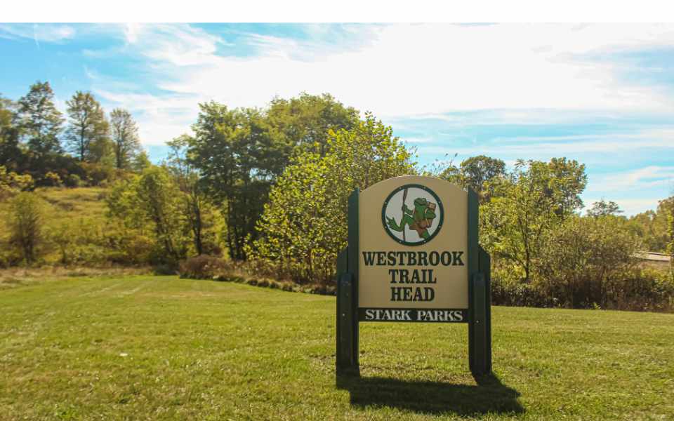 Trailhead sign at Parking Lot with trees and grass in background