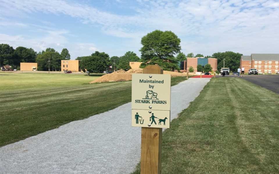 Trail with sign next to it stating maintained by Stark Parks
